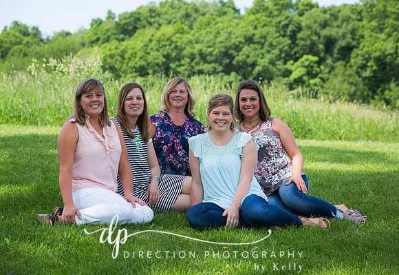 Five women sitting on the grass in the shade of a mighty oak tree
