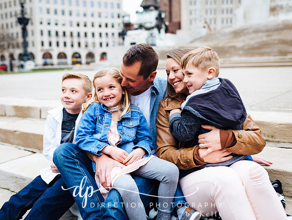 Attractive young family sitting on steps in front of Soldiers and Sailors Monument in Indianapolis IN