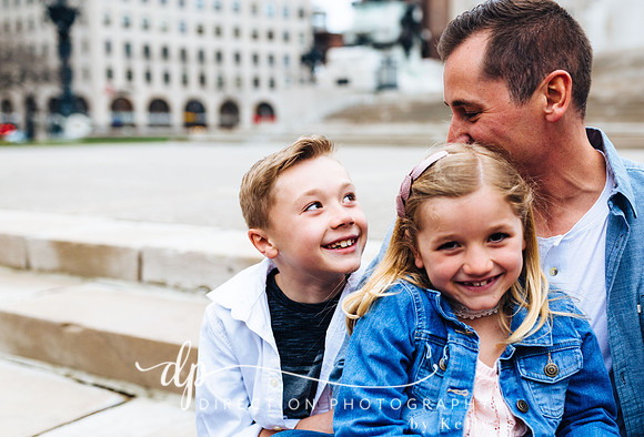 Attractive young family sitting on steps in front of Soldiers and Sailors Monument in Indianapolis IN
